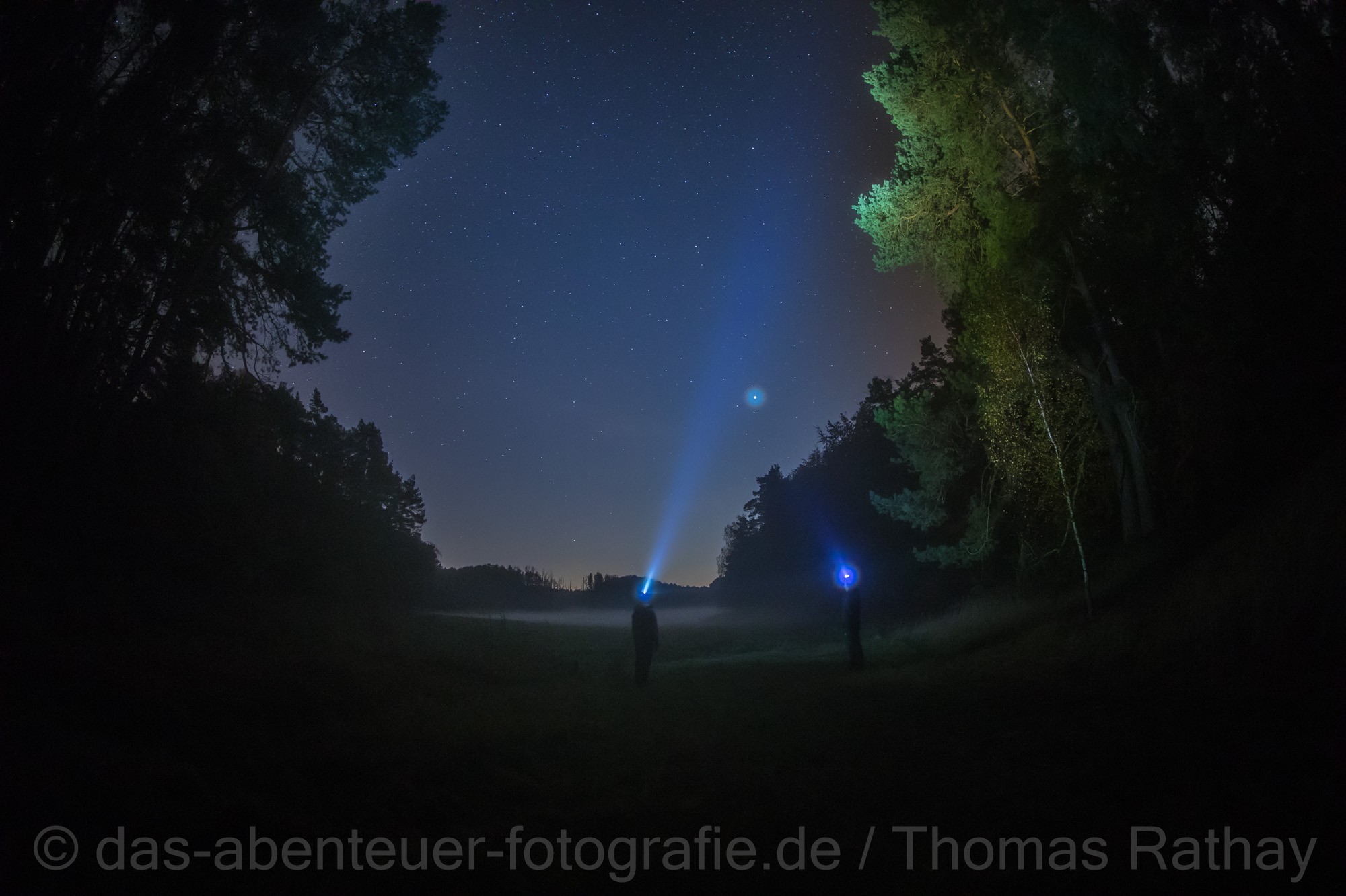 Zwei Fotografen stehen mit Stirnlampen im Dunkel der Nacht - Nachtfotokurs mit Thomas Rathay Zwei Fotografen stehen mit Stirnlampen im Dunkel der Nacht